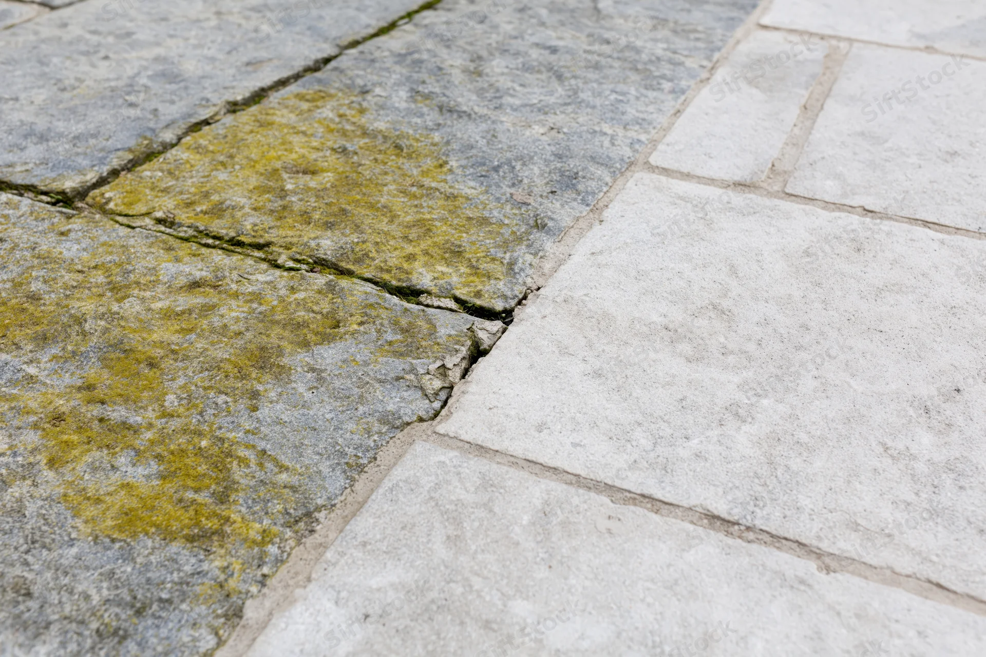 Close-up of weathered stone patio with moss and cracks showing natural aging and outdoor wear
