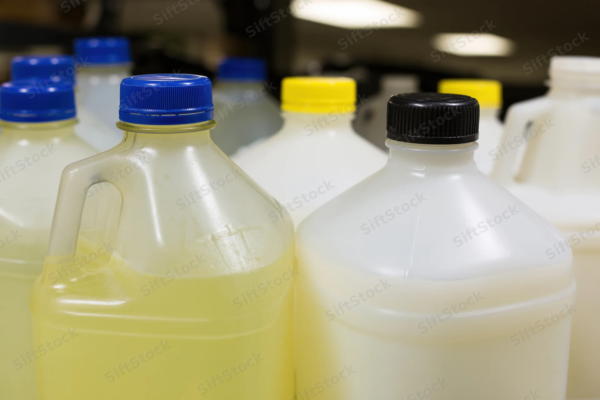 Multiple one-gallon plastic jugs grouped together in a storage area