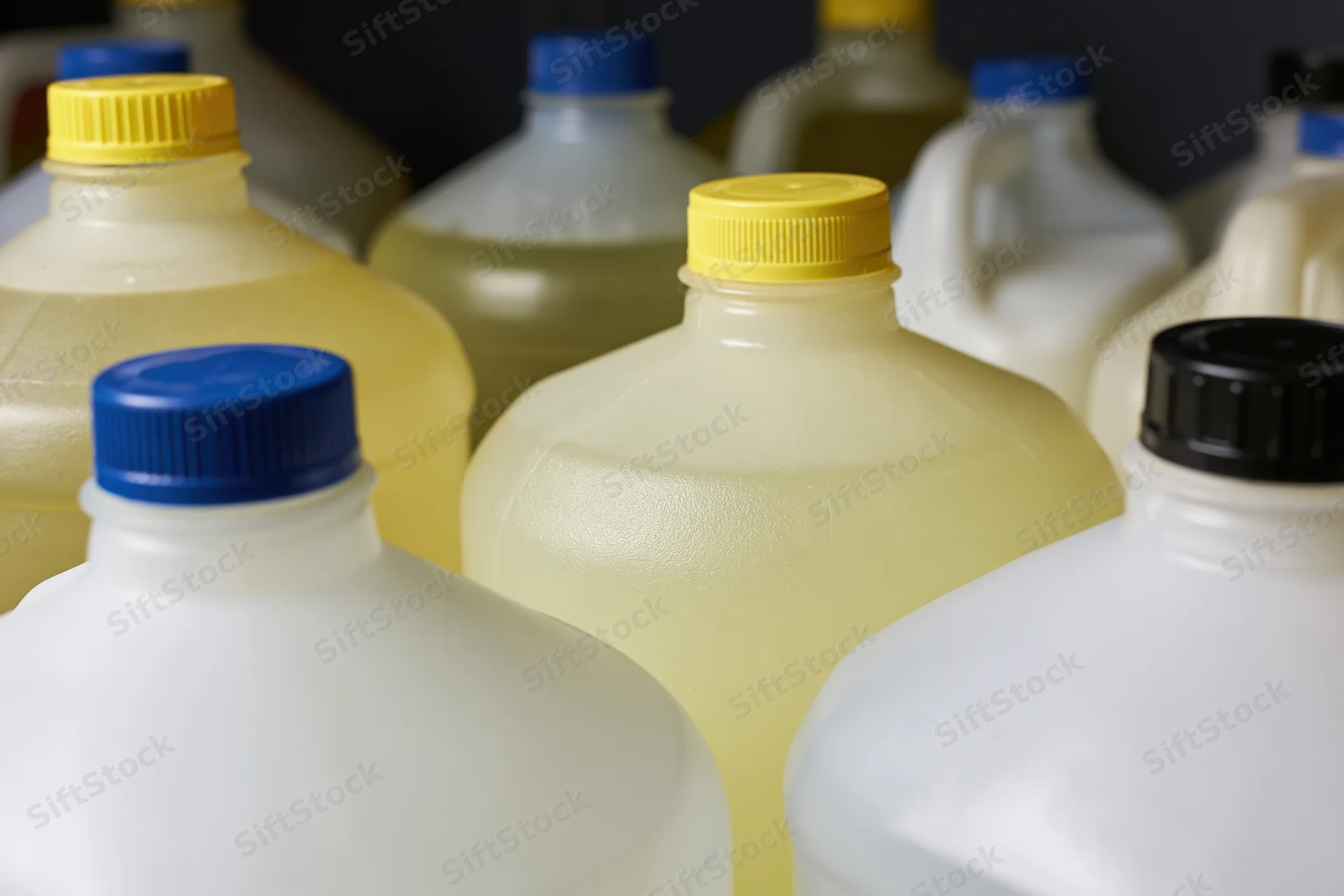 Multiple one-gallon plastic jugs grouped together in a storage setting