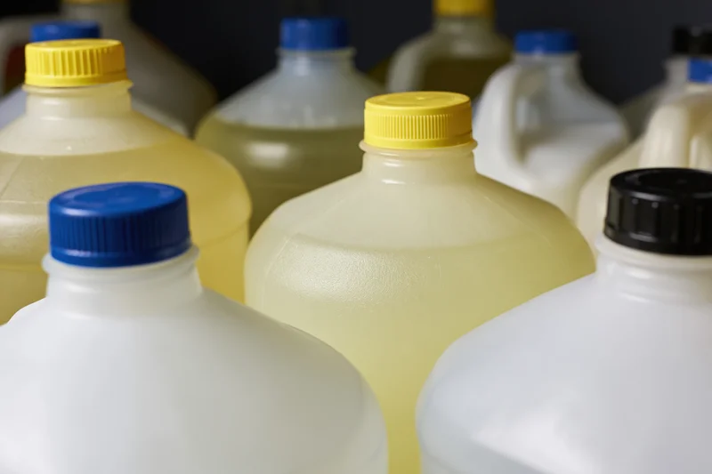 Multiple one-gallon plastic jugs grouped together in a storage setting