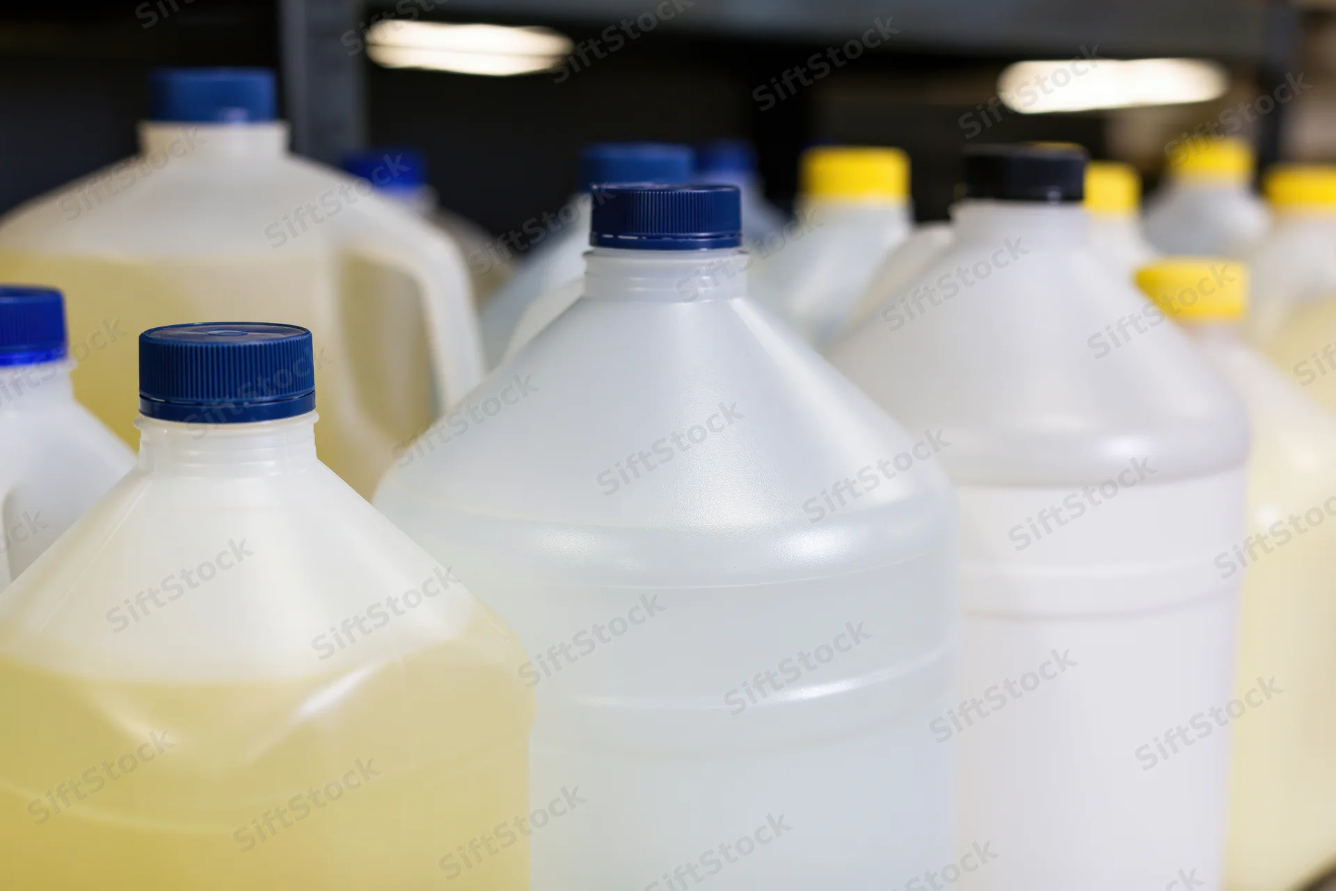 Multiple one-gallon plastic jugs grouped together on warehouse shelves