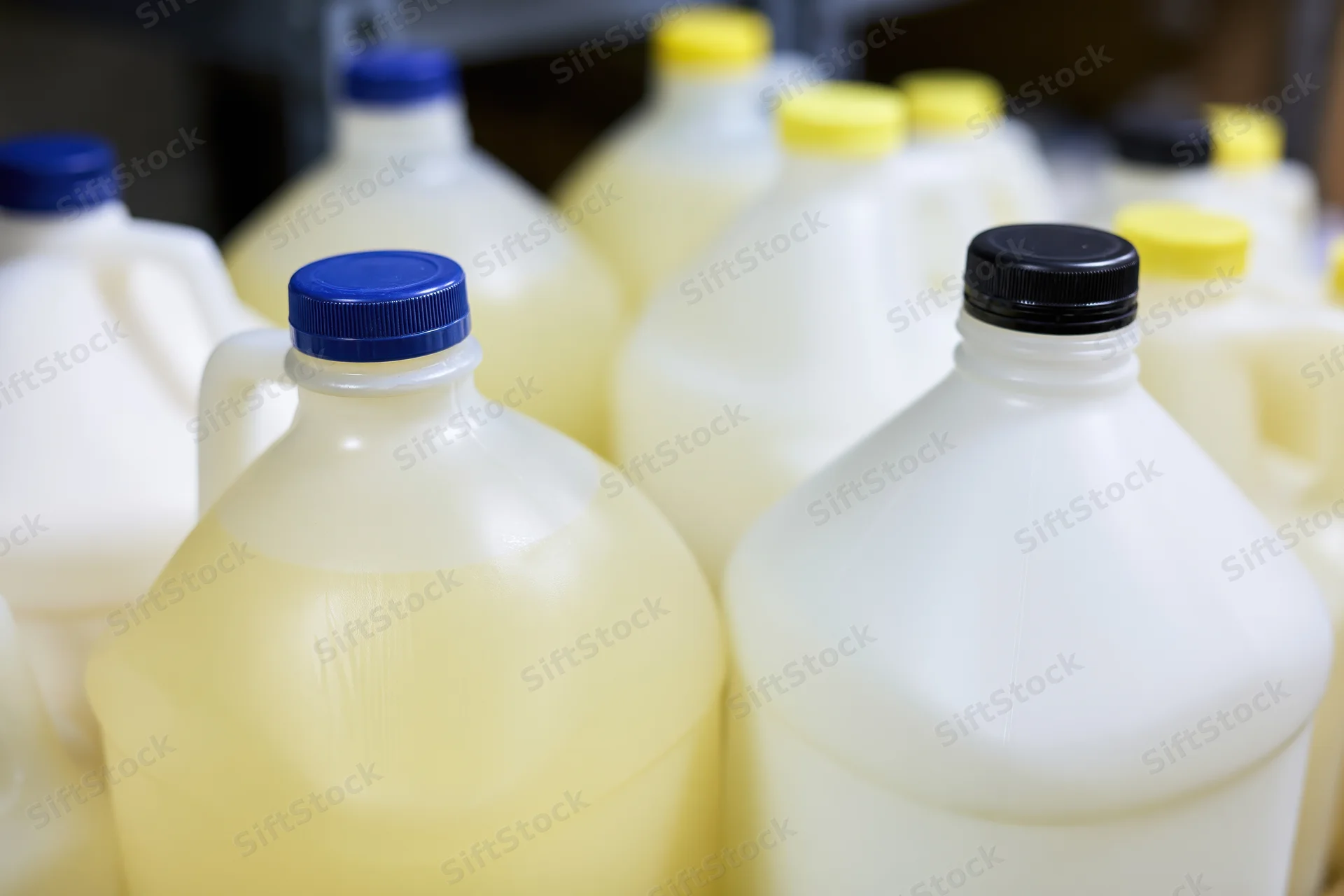 Multiple one-gallon plastic jugs grouped together in a storage area