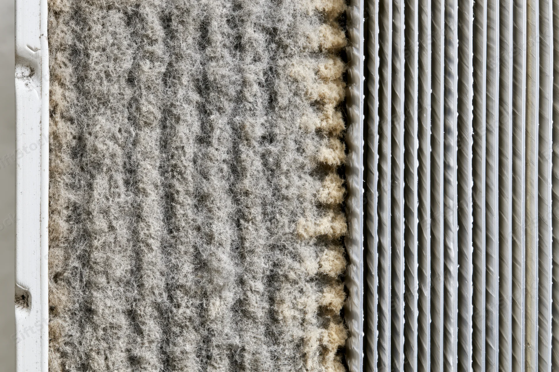 Close-up split view of dirty and clean hvac air conditioner coil fins showing contrast in condition
