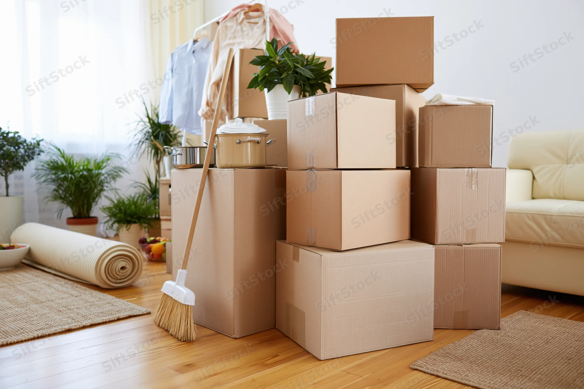 Stacked cardboard boxes and household items in a living room during a move