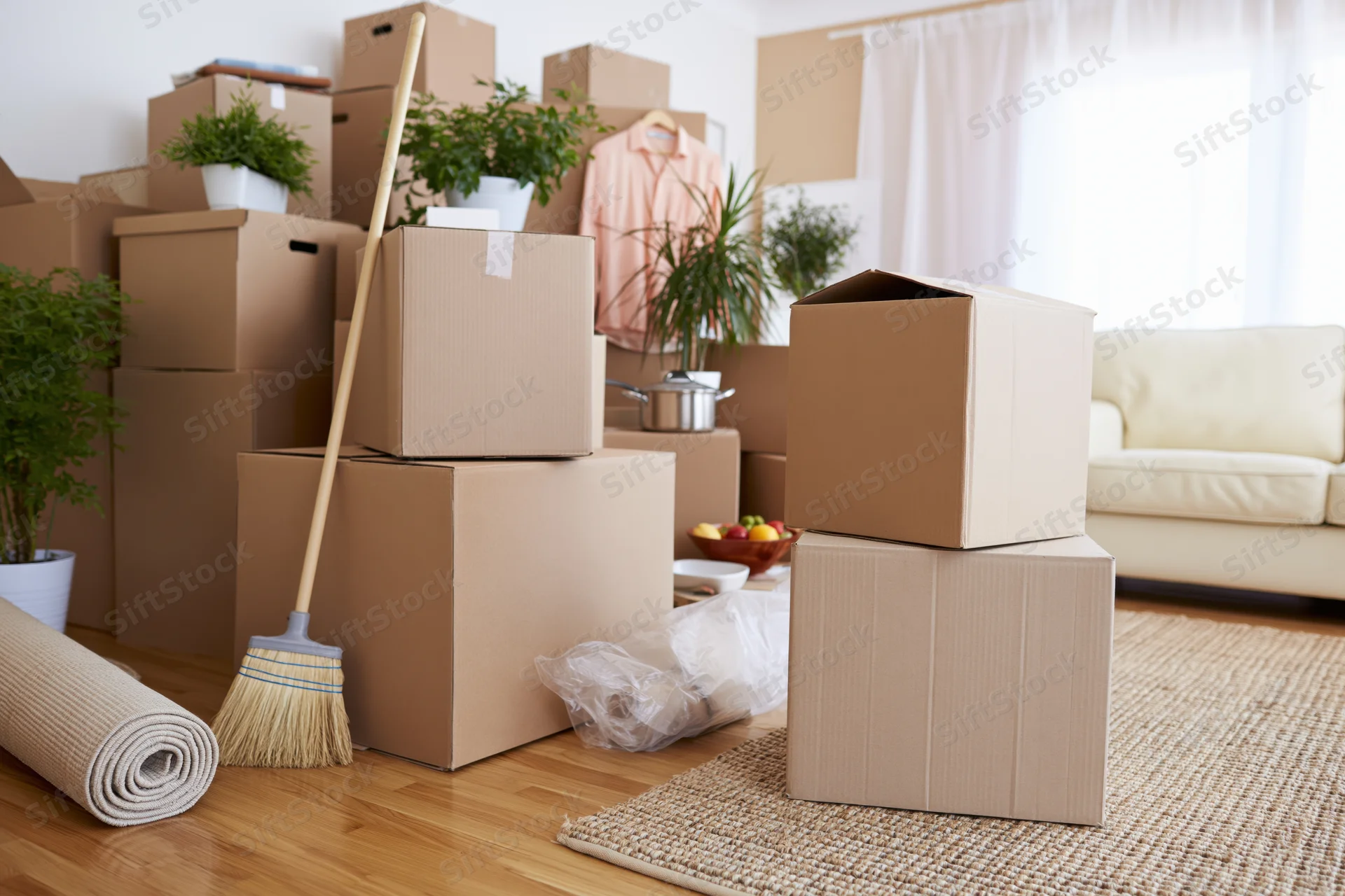Stacked cardboard boxes and household items in a living room during a move