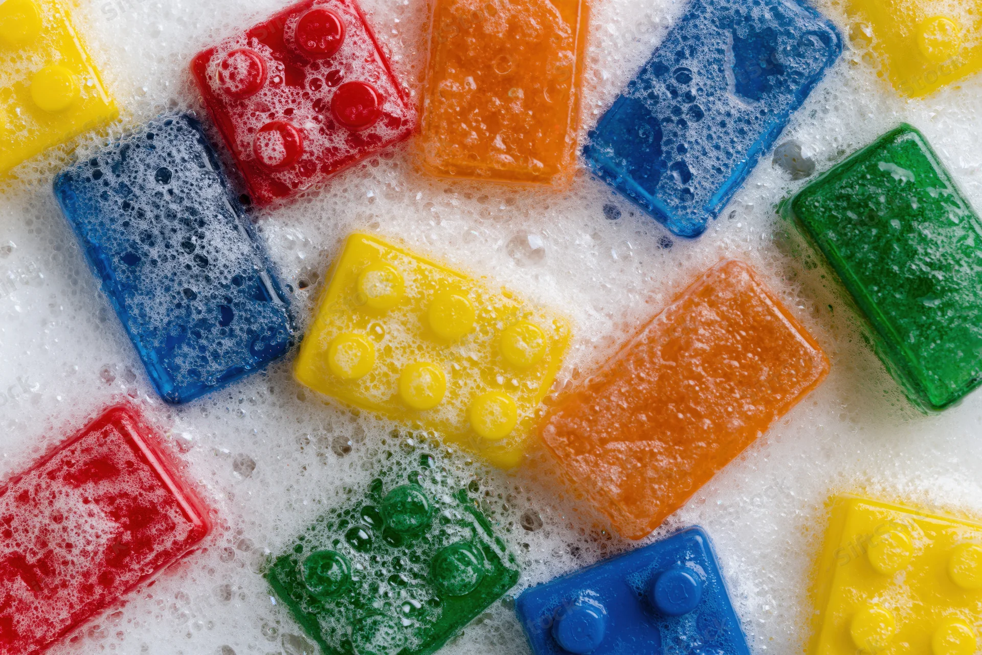 Colorful plastic building blocks submerged in soapy foam during bath time