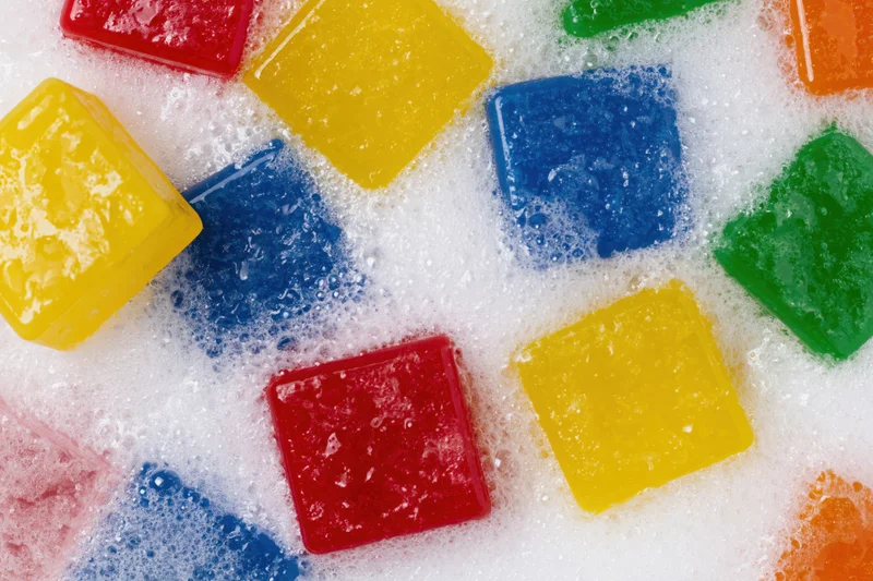Colorful plastic building blocks submerged in soapy water foam