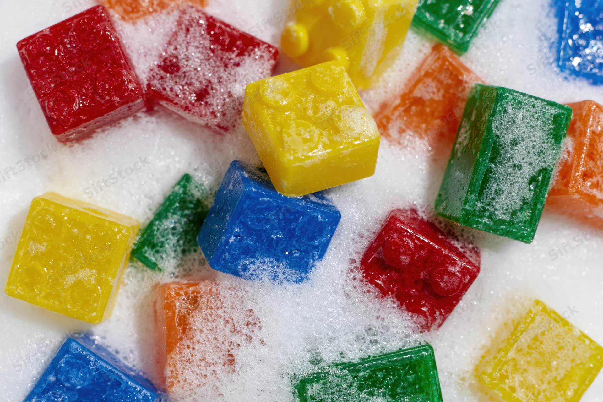 Colorful plastic building blocks scattered and submerged in soapy foam