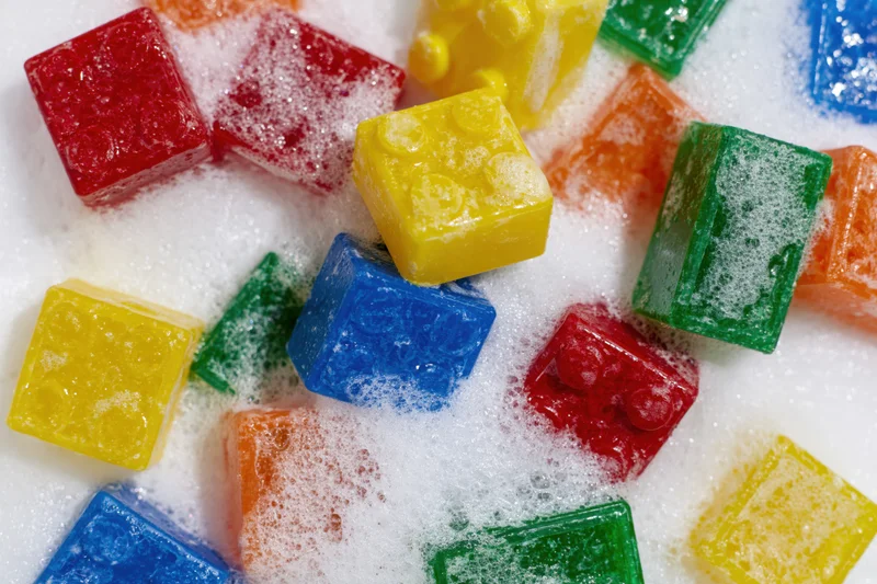 Colorful plastic building blocks scattered and submerged in soapy foam