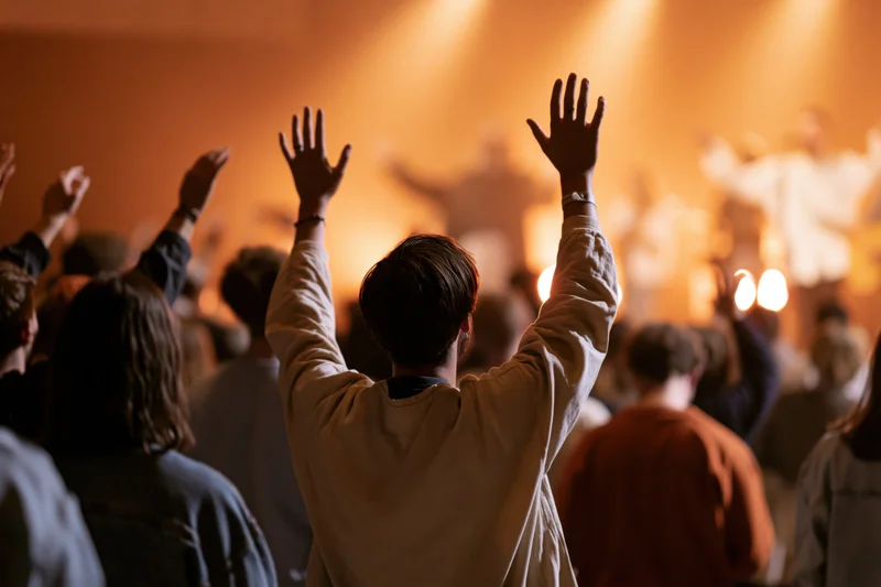 Congregation members raising hands in worship during a live church service