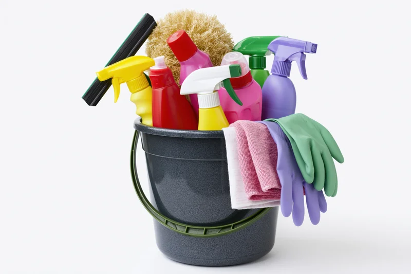 Dark plastic bucket filled with colorful cleaning supplies and gloves on white background