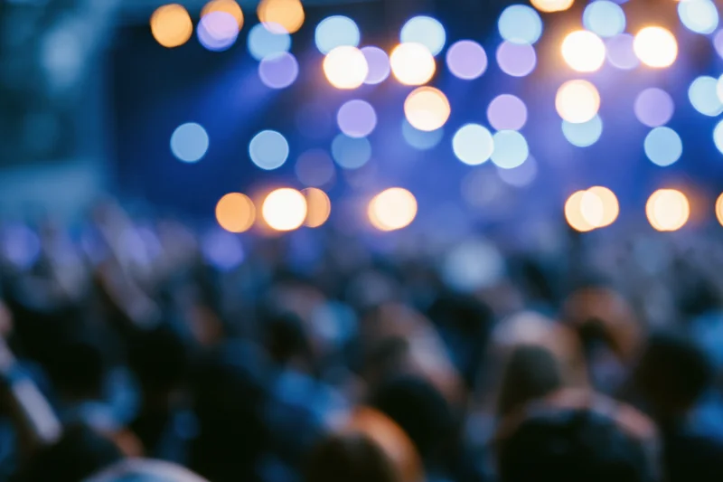 Defocused crowd silhouetted against stage lights at a live music concert