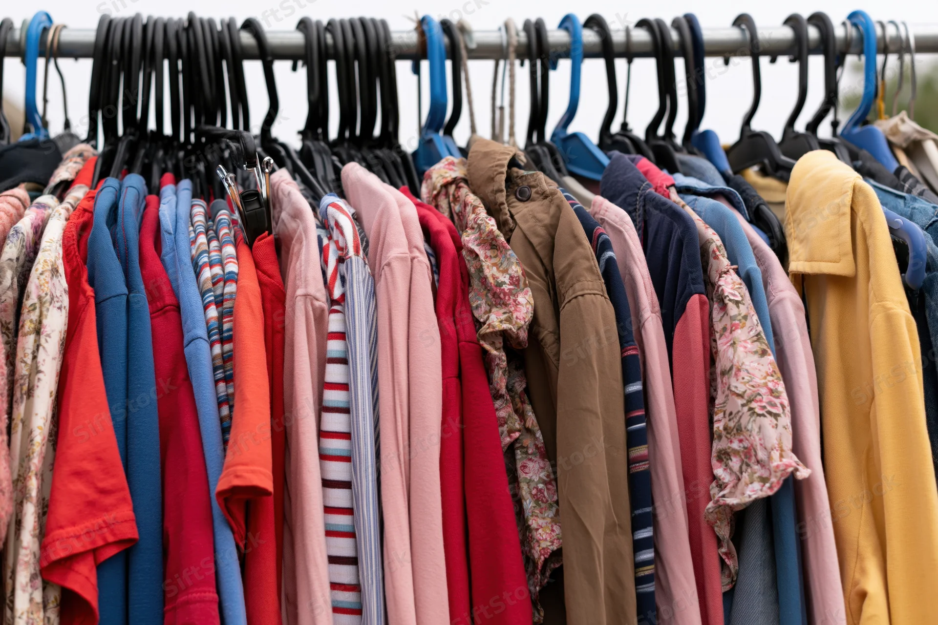 Secondhand clothing densely packed on a metal rack outdoors