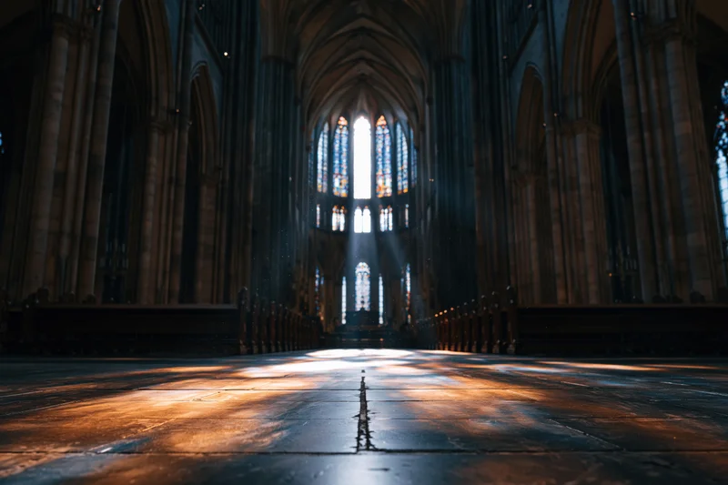 Low-angle view of gothic cathedral interior with sunlight streaming through stained glass toward the altar