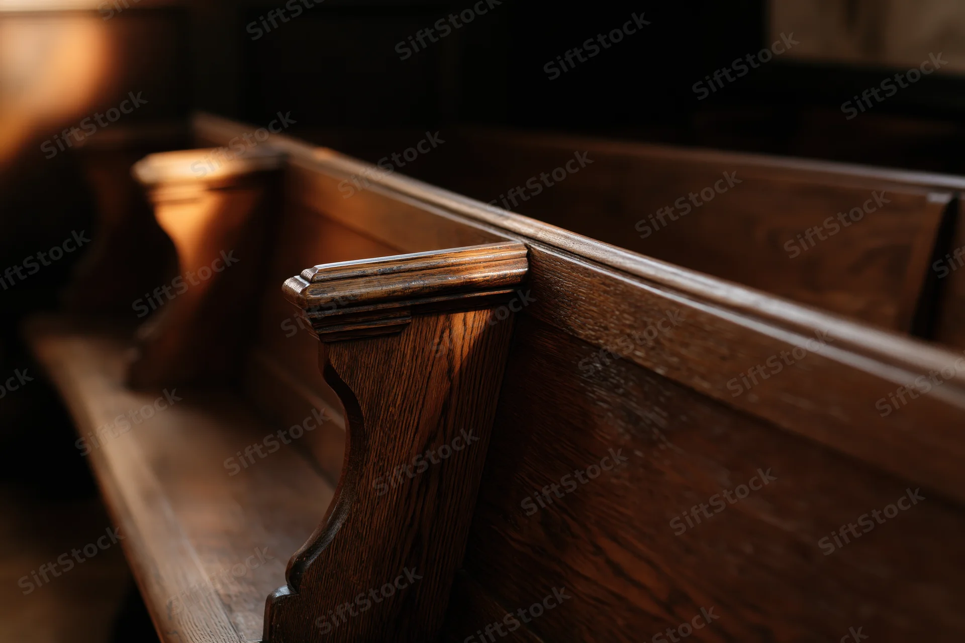 Wooden church pews receding into shadowed interior with warm light highlighting grain and texture