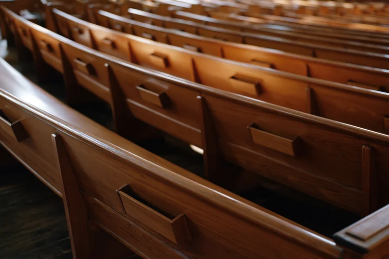 Rows of empty wooden church pews receding into the interior space