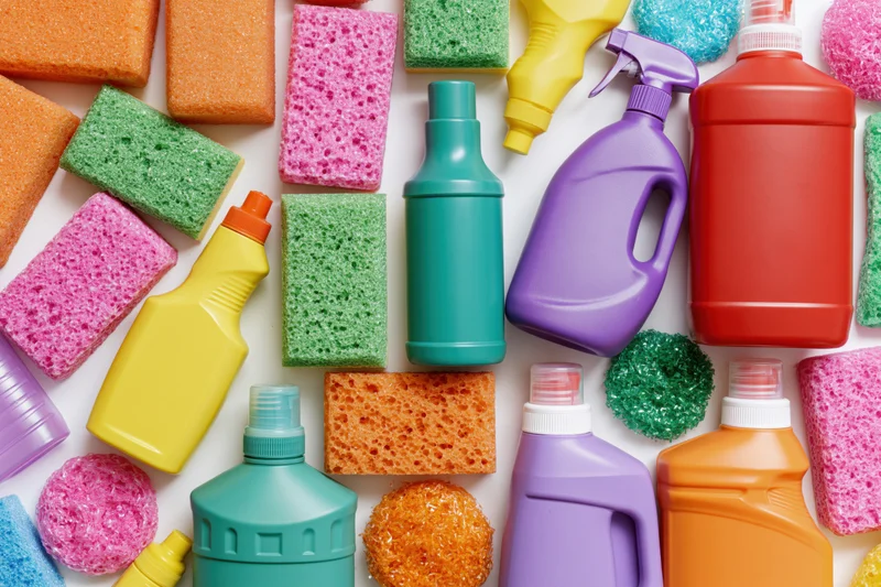 Colorful cleaning supplies and sponges arranged in flat lay on white surface