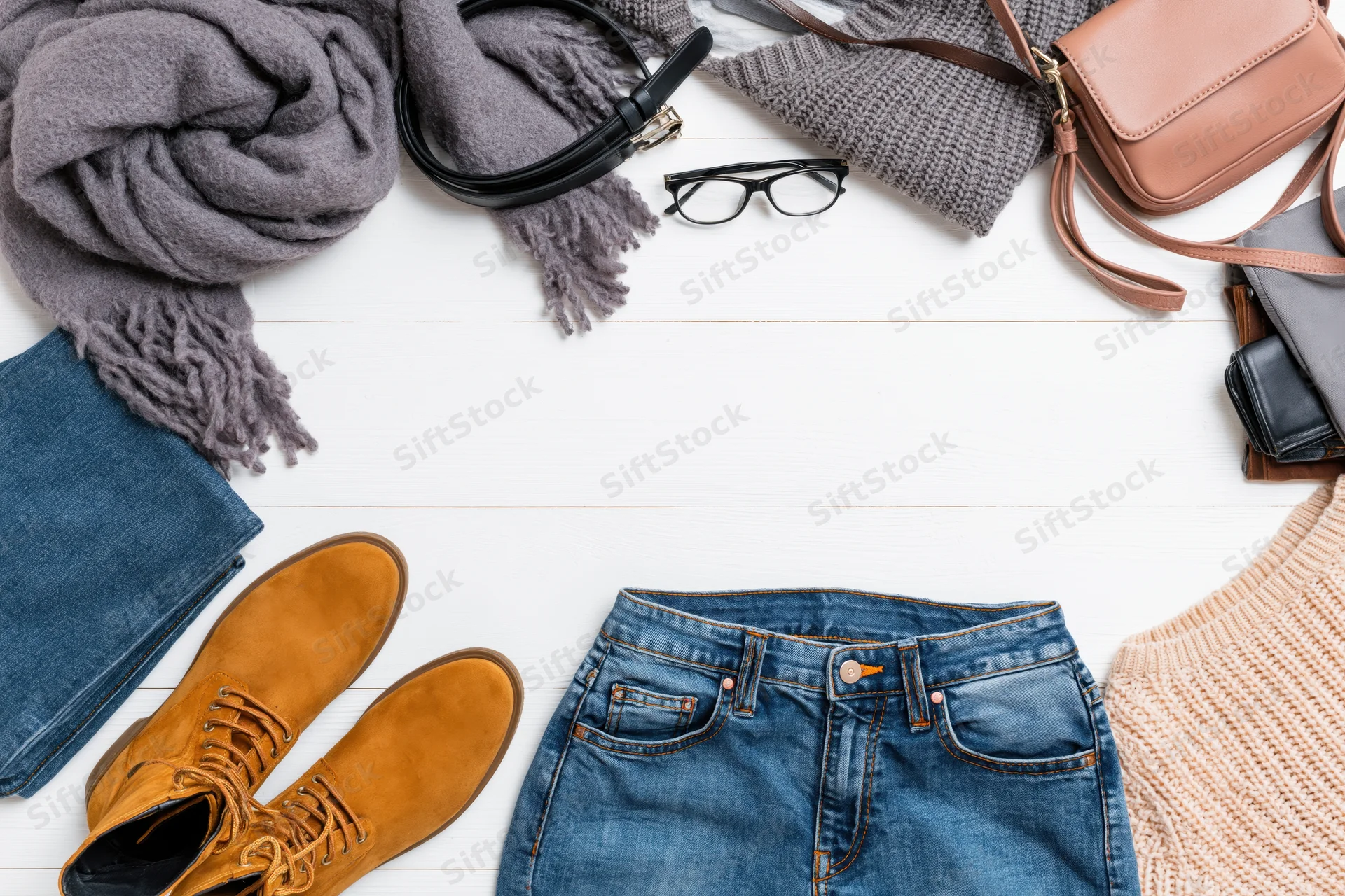 Autumn casual clothing and accessories arranged in a flat lay on white wooden surface