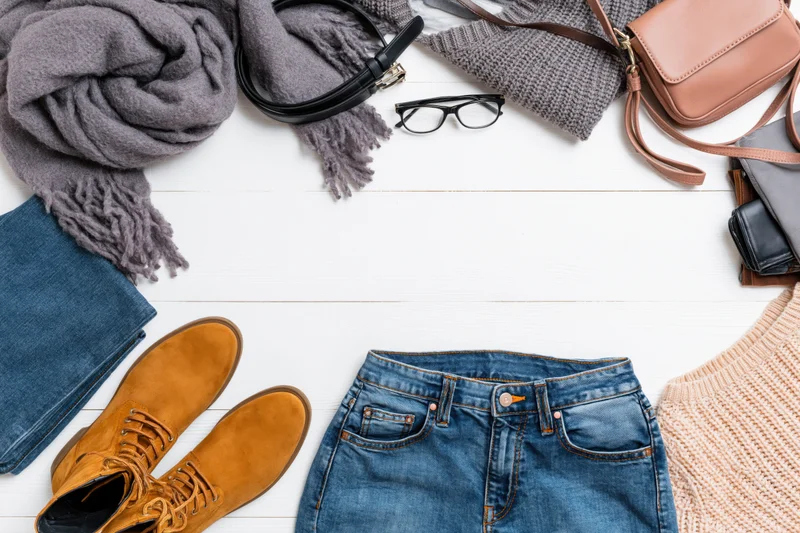 Autumn casual clothing and accessories arranged in a flat lay on white wooden surface