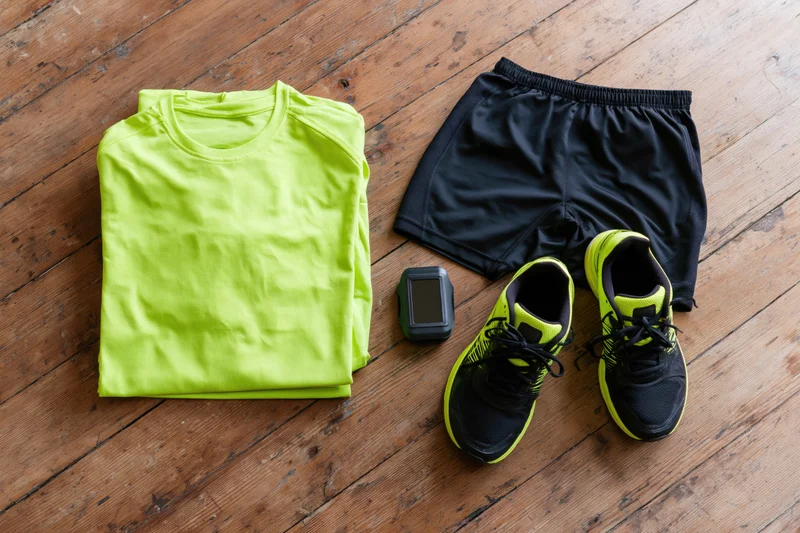 Running gear arranged on a worn wooden floor in flat lay view