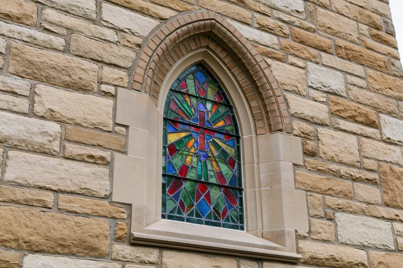 Gothic arched stained glass window set into a limestone church facade