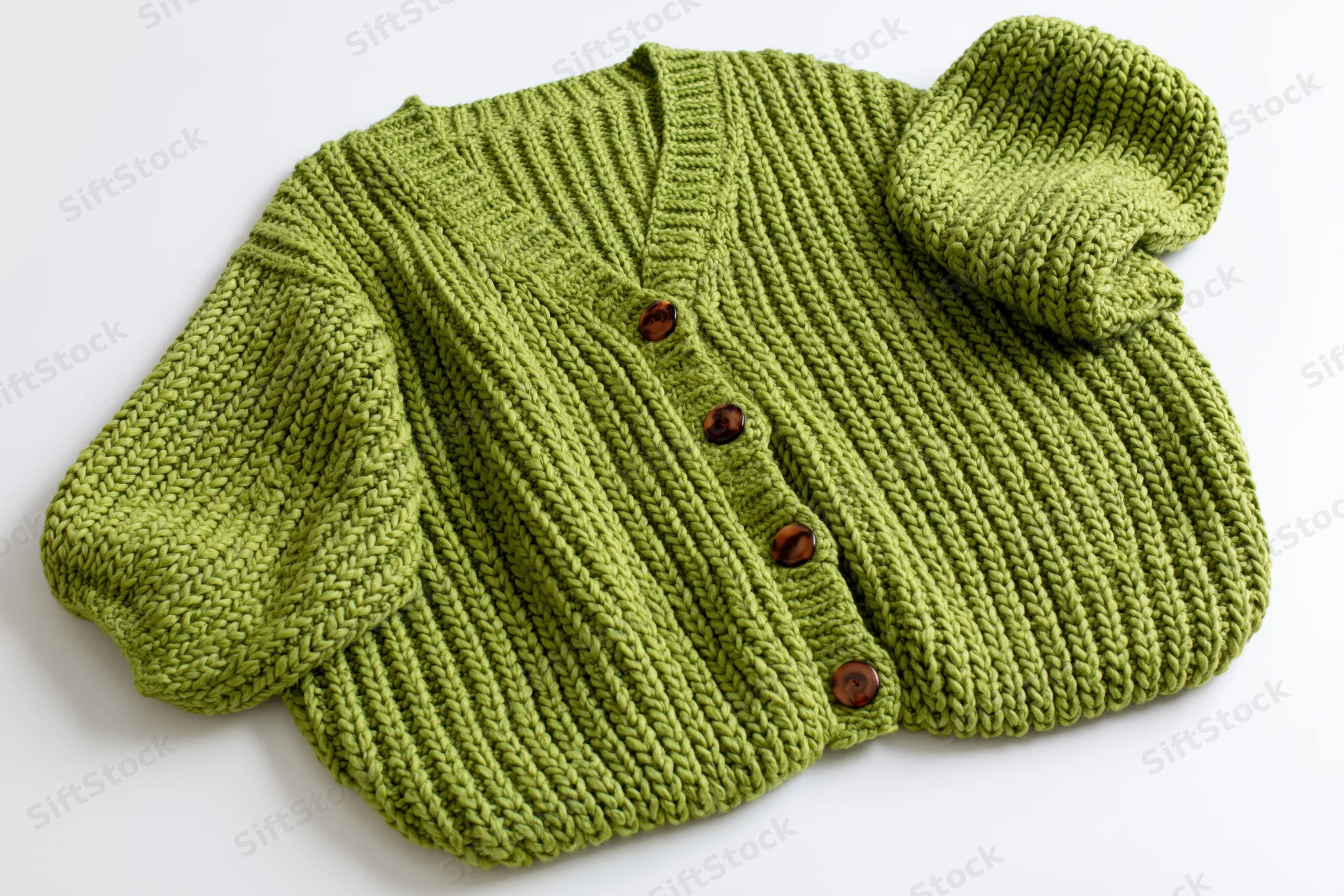 Green knit baby cardigan laid flat with one sleeve raised on white background
