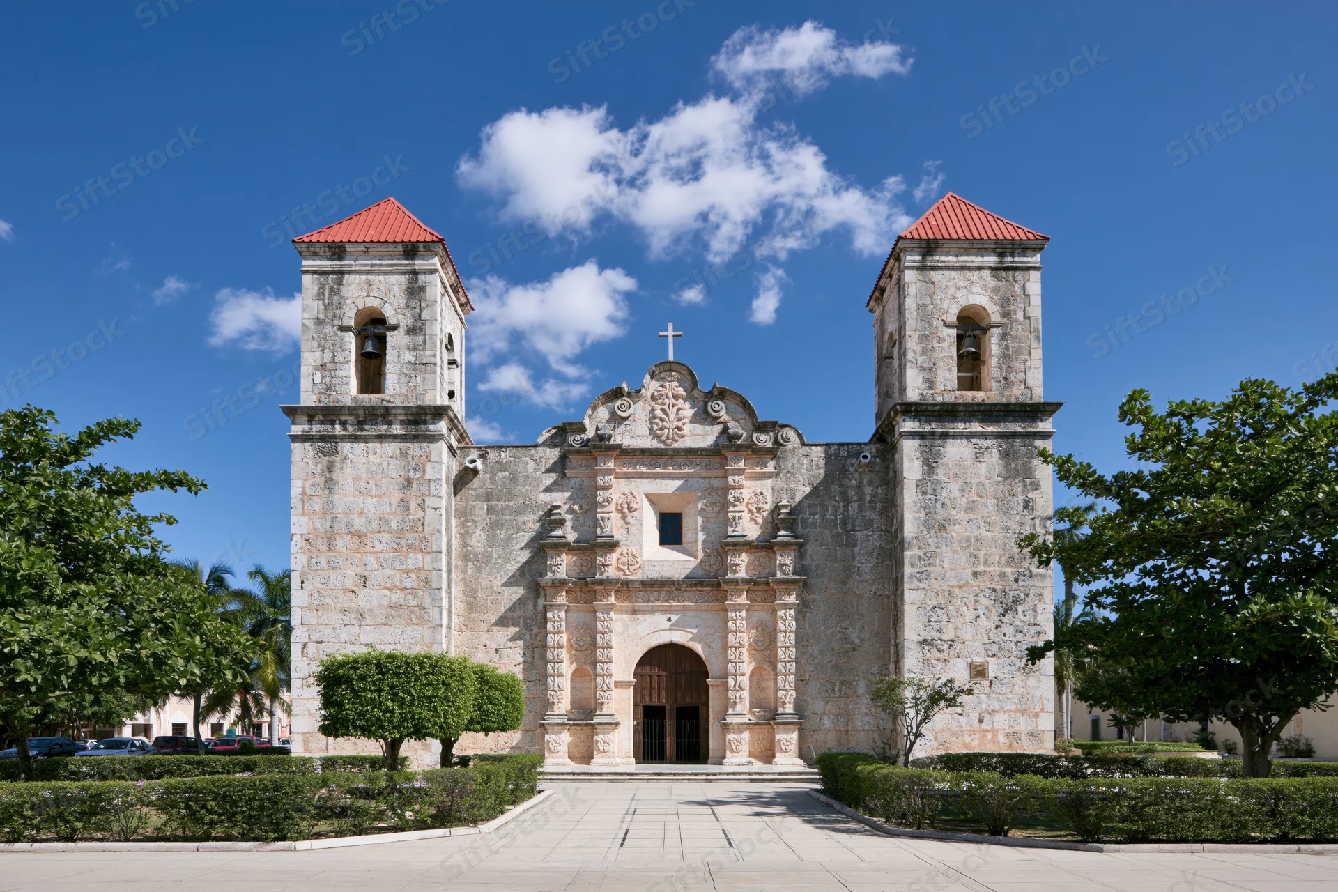 Historic spanish colonial catholic church with twin bell towers and ornate stone facade under blue sky