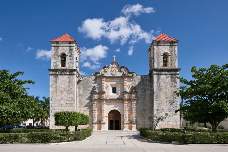 Historic spanish colonial catholic church with twin bell towers and ornate stone facade under blue sky
