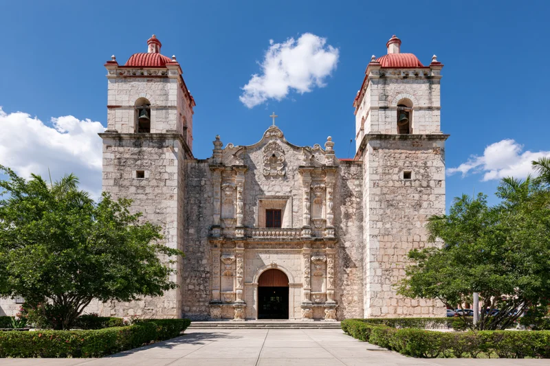 Historic spanish colonial catholic church with twin bell towers and stone facade under blue sky