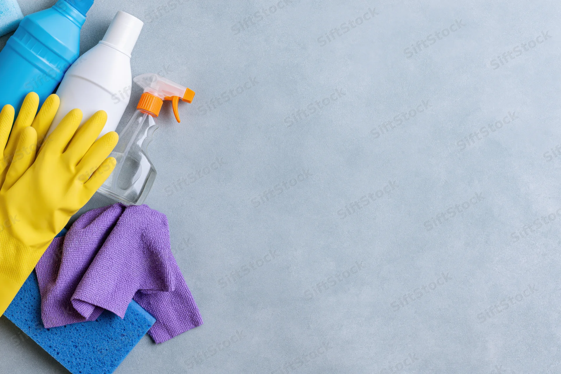Cleaning supplies arranged in upper-left corner on gray surface