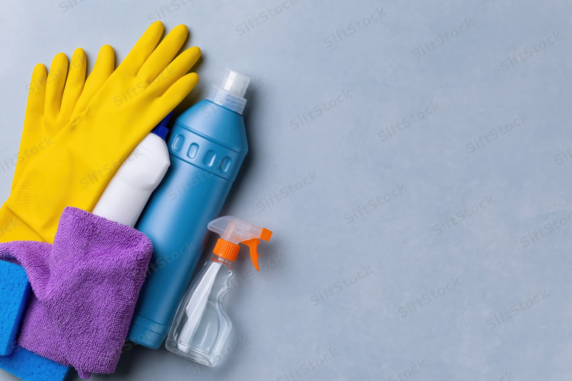 Cleaning supplies arranged in upper-left corner on gray surface