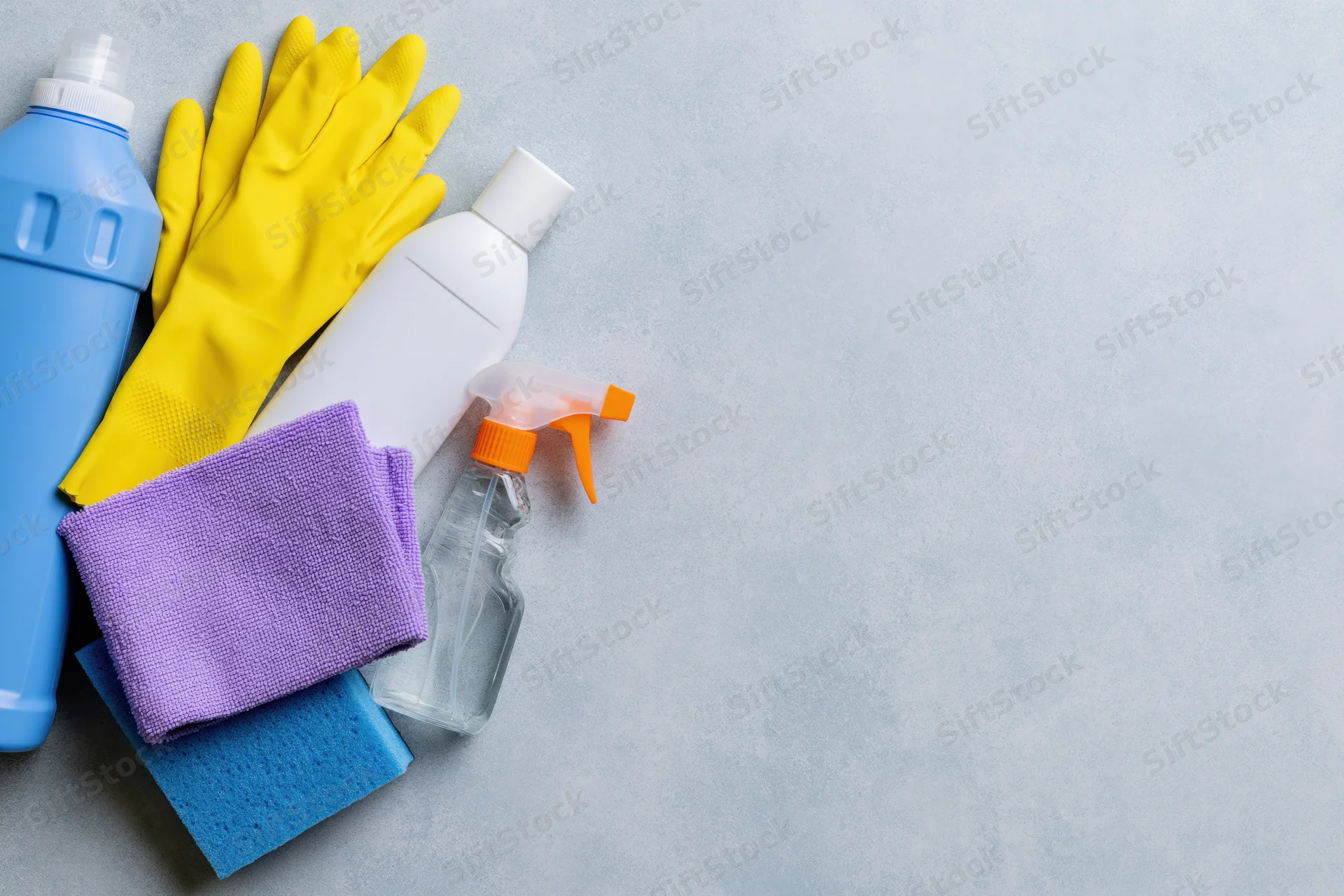 Household cleaning supplies arranged in the upper-left corner on a gray surface