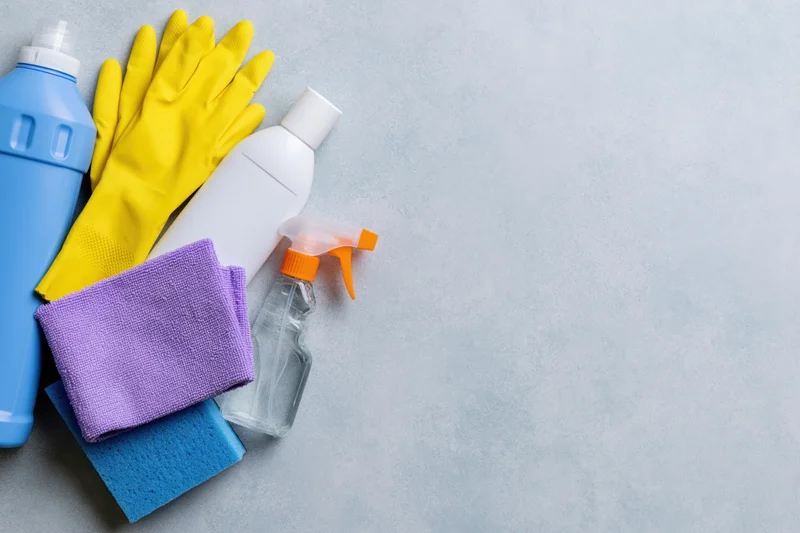 Household cleaning supplies arranged in the upper-left corner on a gray surface