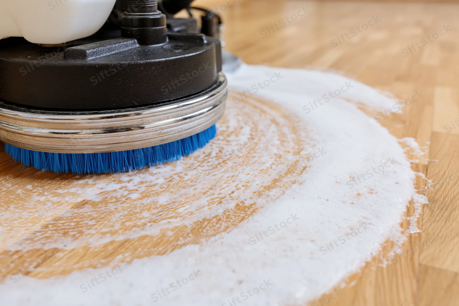 Industrial floor polishing machine with blue rotating brush cleaning hardwood floor with foam