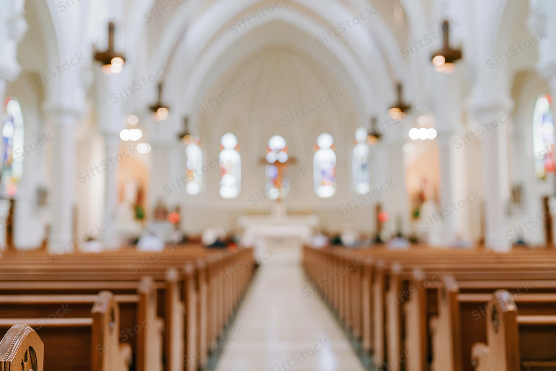 Interior of a catholic church nave with wooden pews and arched ceiling leading to altar