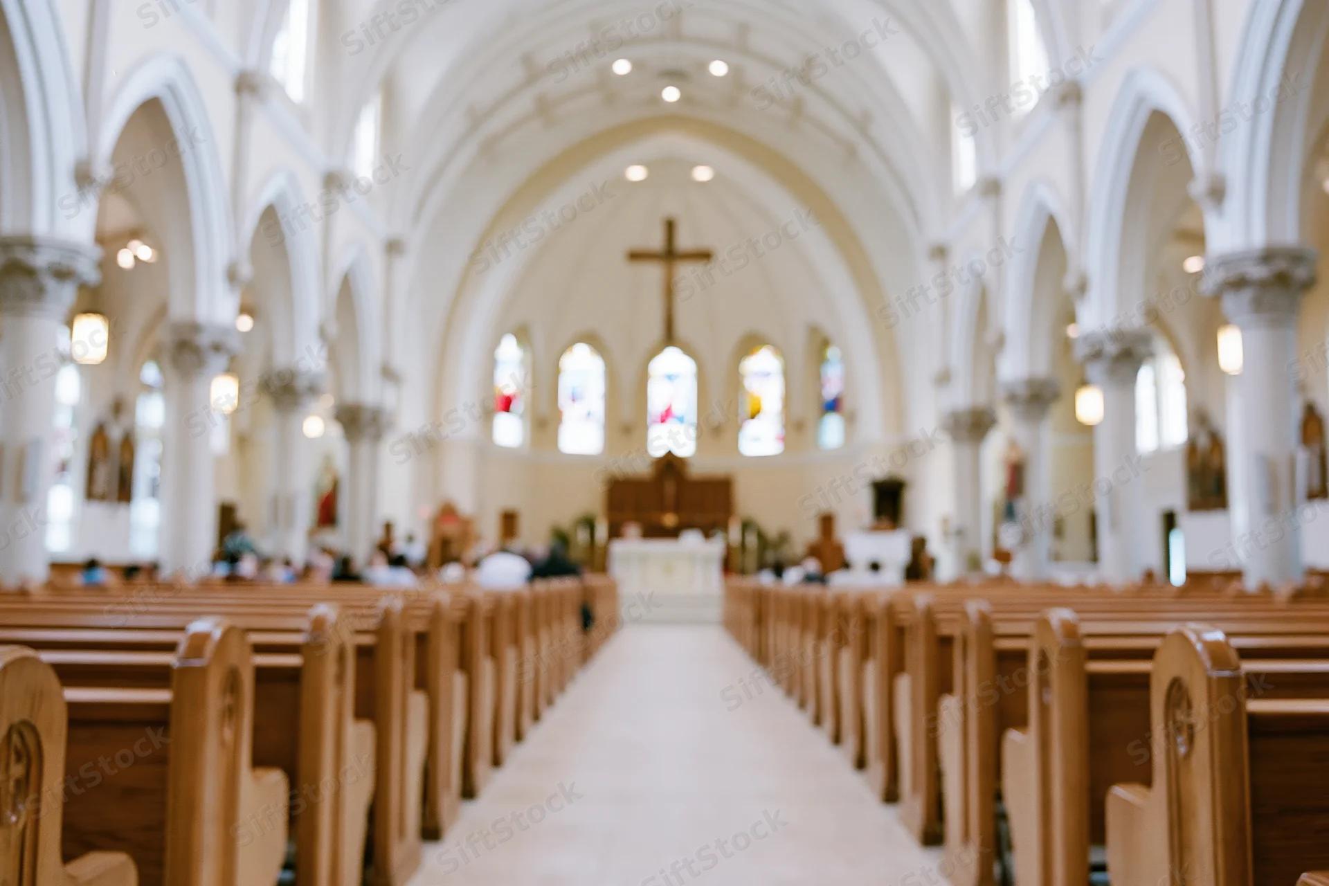 Interior of catholic church nave with wooden pews and arched ceiling leading to altar and cross