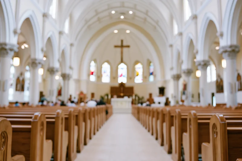 Interior of catholic church nave with wooden pews and arched ceiling leading to altar and cross