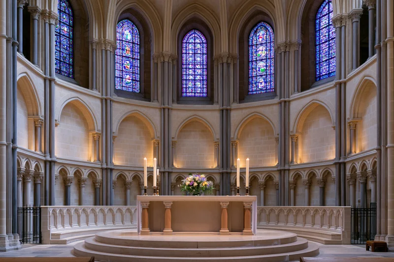 Wide symmetrical view of a gothic cathedral apse with altar and stained glass windows