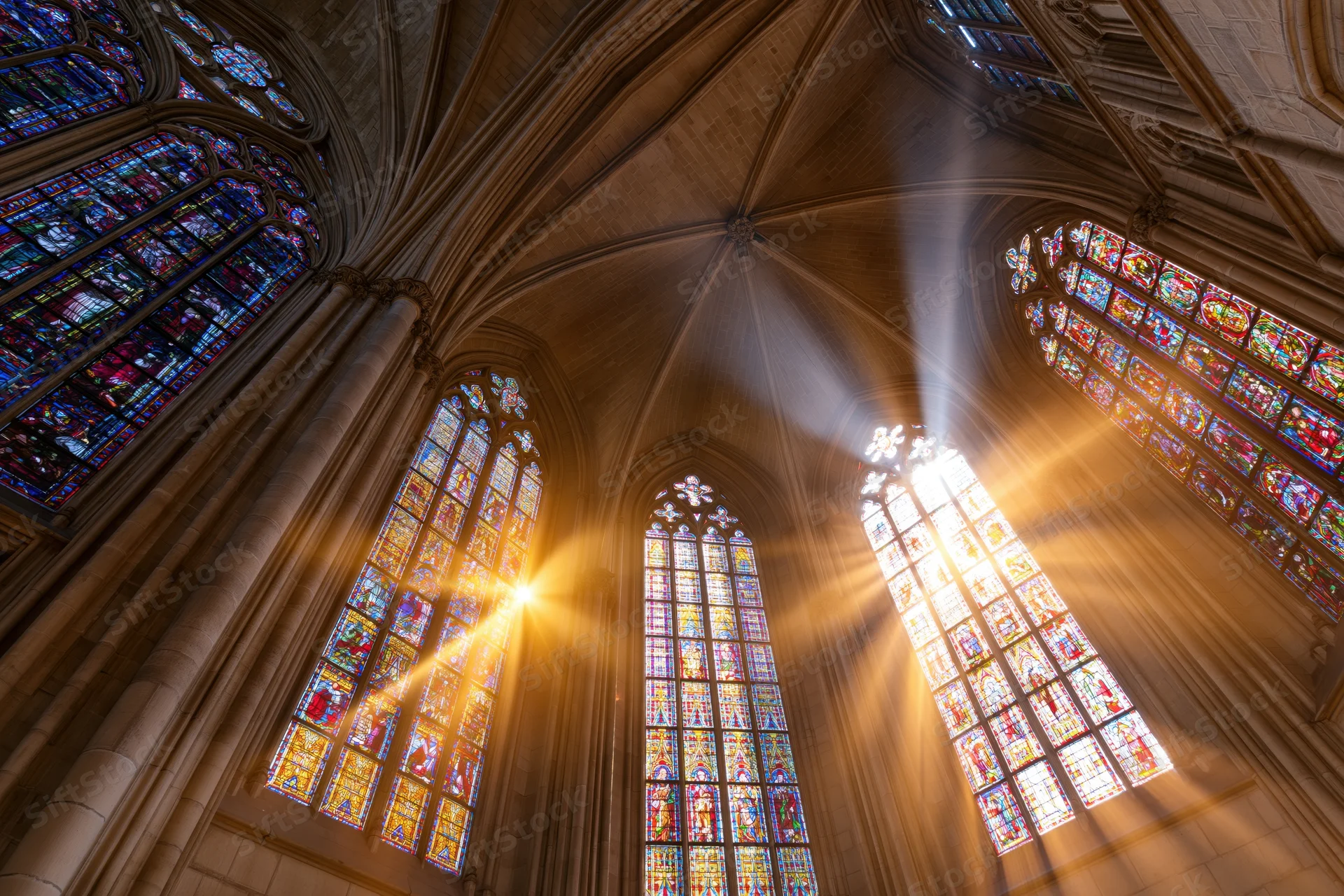 Sunlight streaming through stained glass windows in a gothic cathedral nave