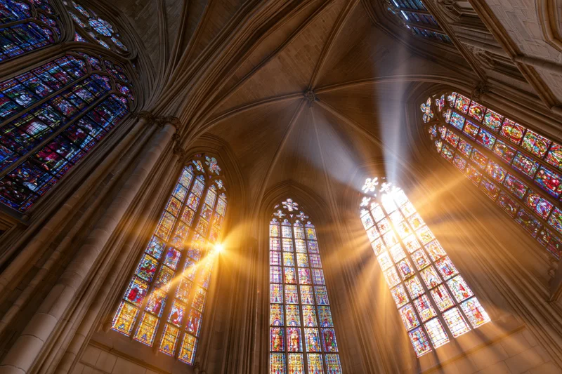 Sunlight streaming through stained glass windows in a gothic cathedral nave