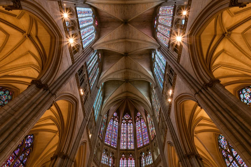 Upward view of gothic cathedral nave with vaulted stone ceiling and stained glass windows