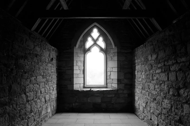 Dark stone chapel interior with tall gothic window letting in light