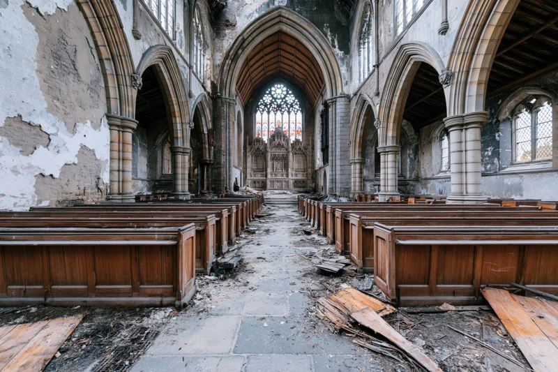 Abandoned gothic church nave with damaged pews and debris along the central aisle