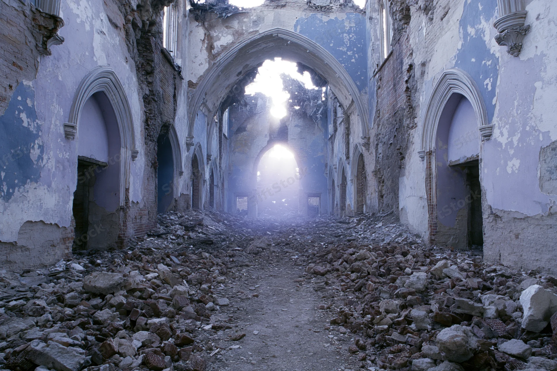 Crumbling gothic-arched interior of an abandoned hall filled with rubble and broken walls