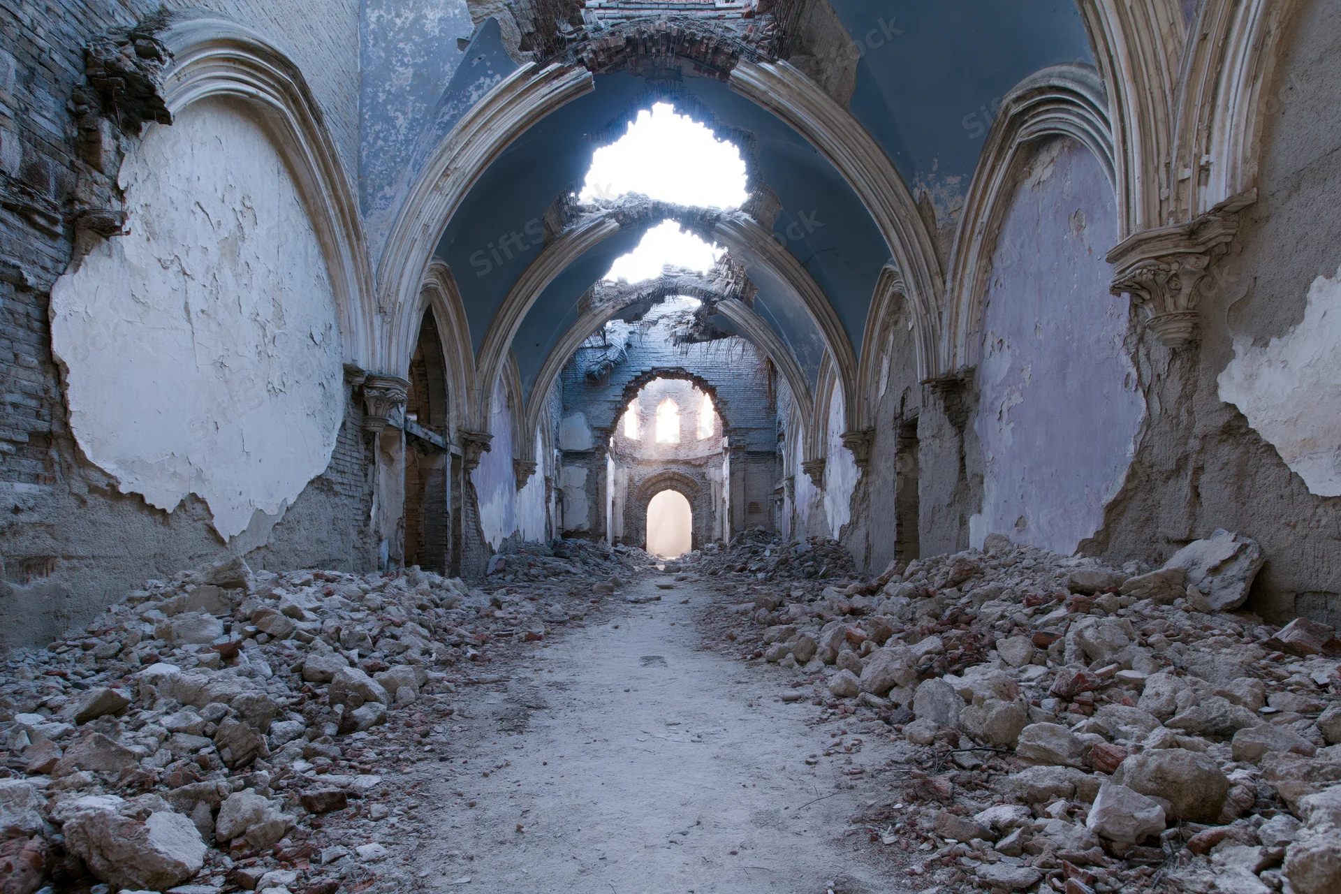 Crumbling gothic arched interior of abandoned hall with rubble and broken ceiling