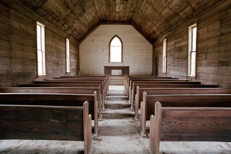 Empty wooden pews in a rural abandoned church interior with dirt floor and arched windows