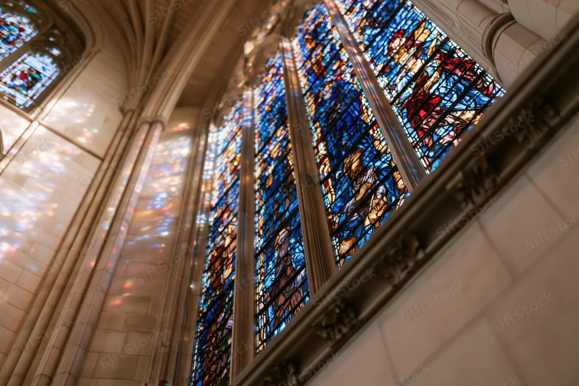 Low-angle view of large stained glass window in gothic cathedral interior