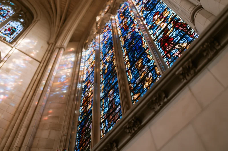 Low-angle view of large stained glass window in gothic cathedral interior