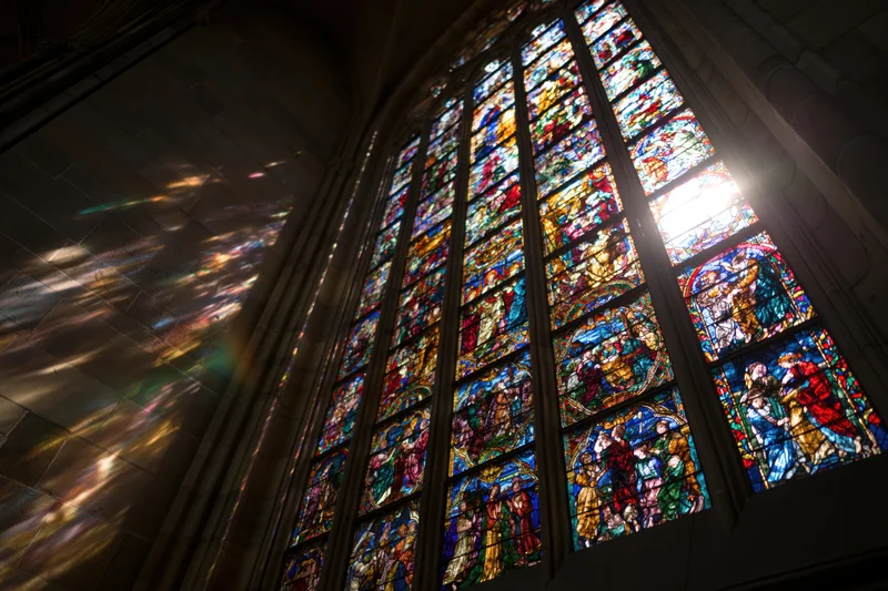 Large gothic stained glass window in cathedral interior glowing with backlit light