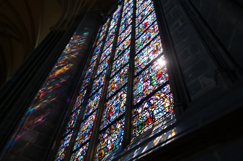 Large gothic stained glass window glowing with sunlight in cathedral interior